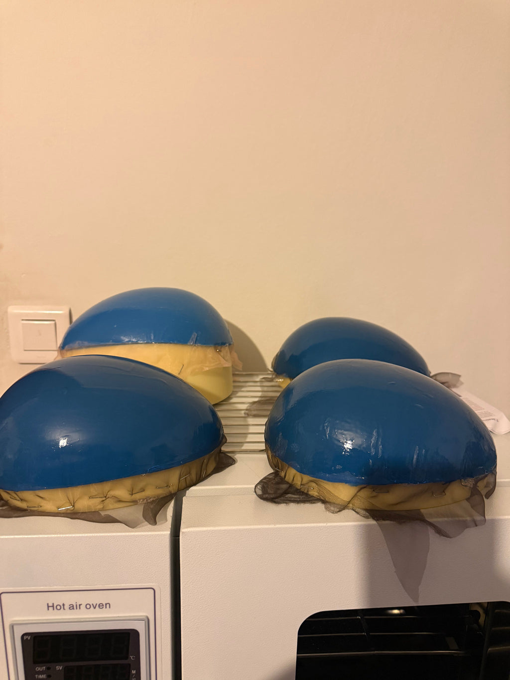 Support en caoutchouc incurvé pour l'injection de mèches de cheveux sur une micro-peau en vue de la fabrication de prothèses capillaires.